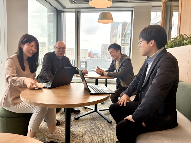 取材に応じる関係者4名の集合写真。前列左に北國銀行の北本氏、右にデジタルバリューの杉村氏、後列左にCCイノベーションの又多氏、右に馬場氏が座り、笑顔でカメラを向いている。